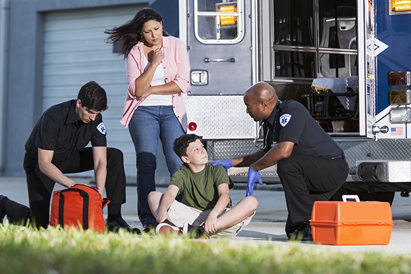 Paramedics helping boy with mother watching