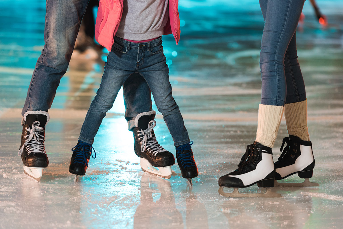 cropped shot of young family in skates skating together on rink
