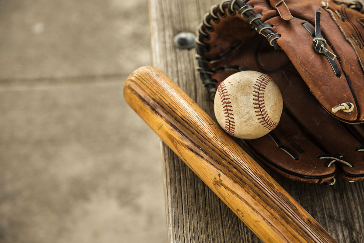 Baseball season is here. Bat, glove and ball on dugout bench.